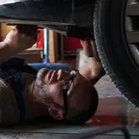 auto mechanic checking undercarriage of car