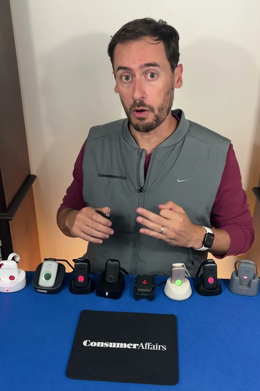 Chris at the test table, explaining, with a row of medical alert pendants in front of him