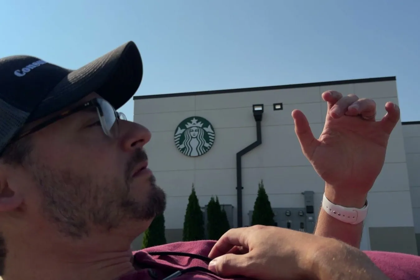 Chris lying on his back in front of a Starbucks after a test fall, one hand raised