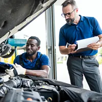 mechanic and manager inspecting car engine