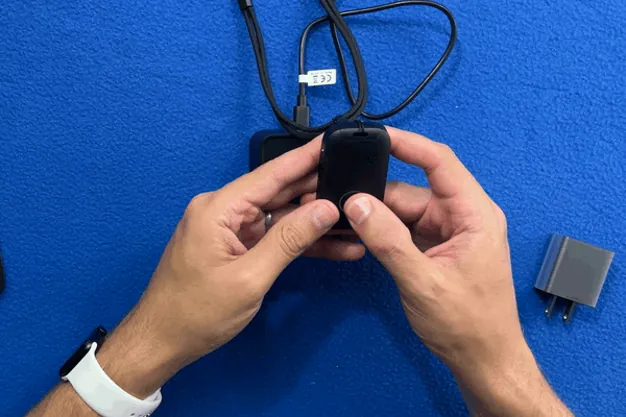 Hands pressing and holding the MobileHelp Elite help button until the ring lights red
