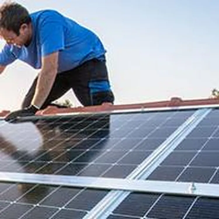 worker installing solar panels on roof