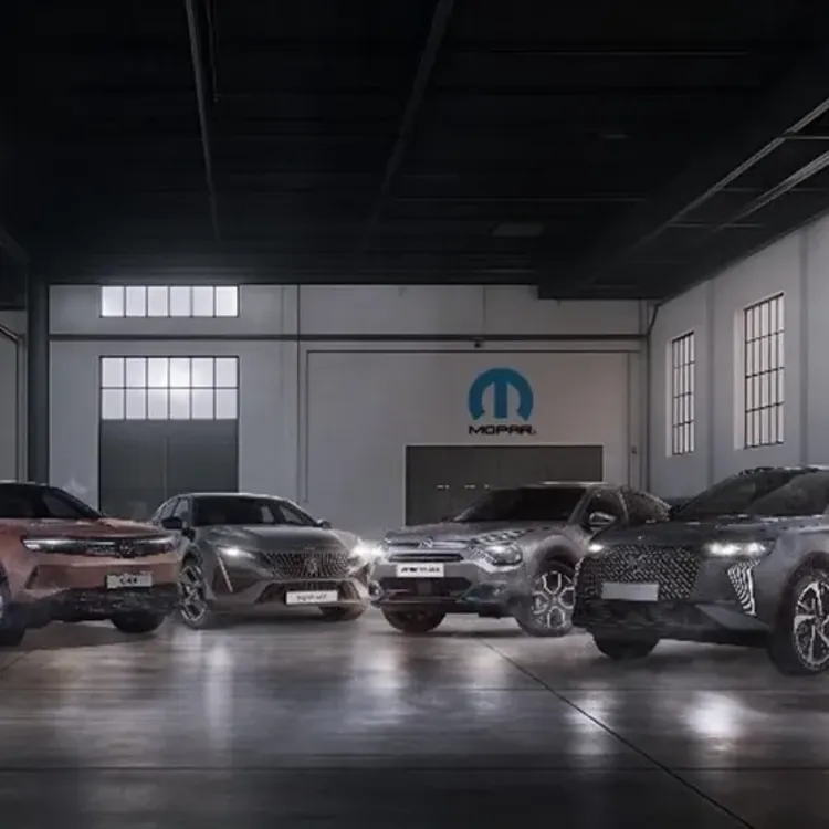 Several cars and SUVs parked side by side inside a large indoor garage with high windows