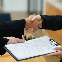 home buyer and agent shaking hands over a closed contract