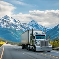 a moving truck on a highway with snowy mountains in the background