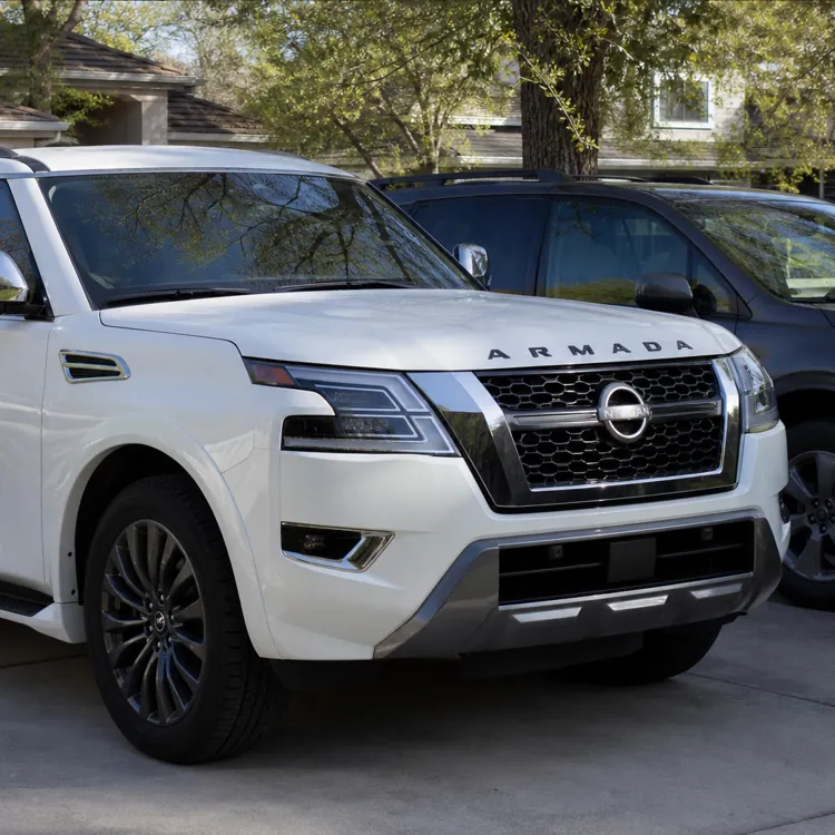 A white Nissan Armada SUV parked in a quiet suburban driveway