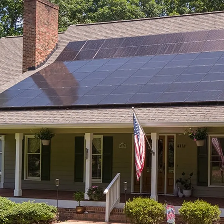 A house with solar panels installed across most of its roof above a covered front porch.
