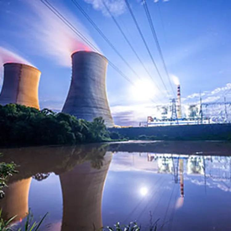 power plant releasing pinkish steam and a factory on the background