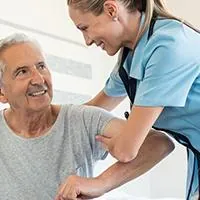 nurse helping elderly man out of bed
