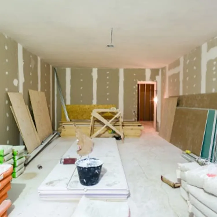 Room under construction with unfinished drywall, stacked materials, and construction tools