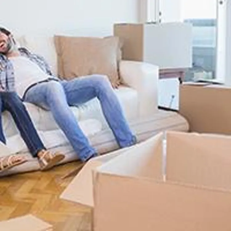 couple sitting on a couch surrounded by moving boxes