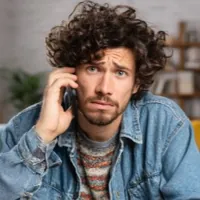 a guy holding a phone over his ear looking concerned