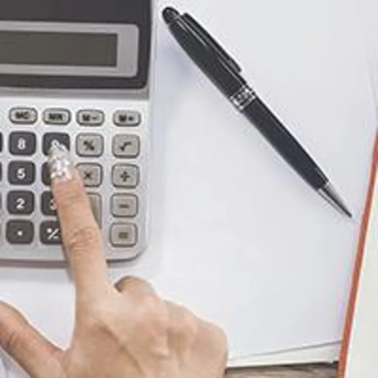 person holding credit cards and typing numbers into a calculator