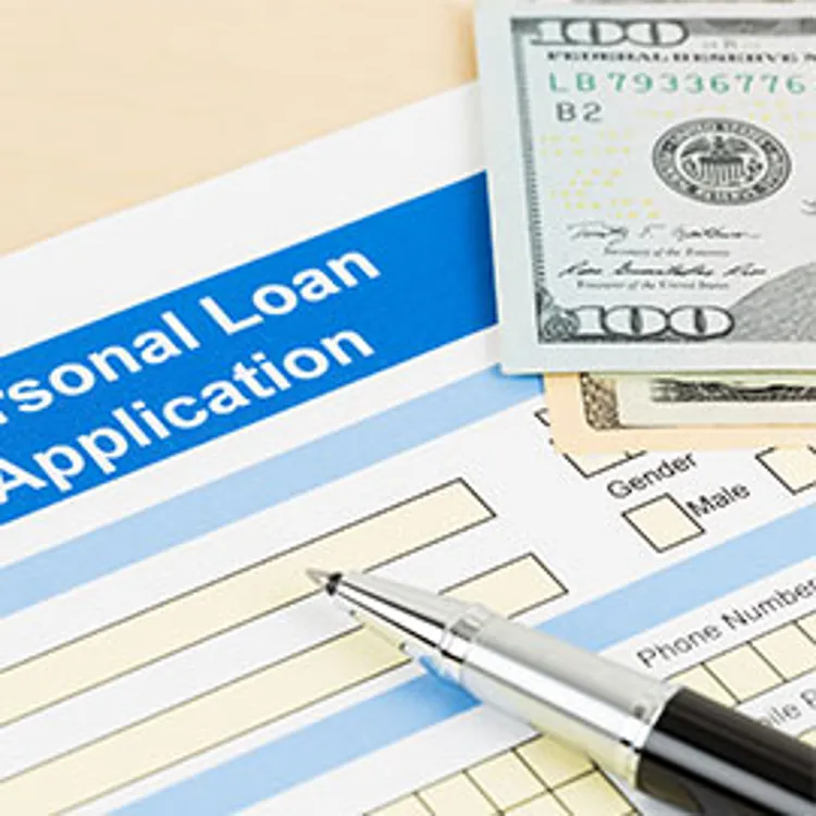 Personal loan application paper, pen and money on top of a table