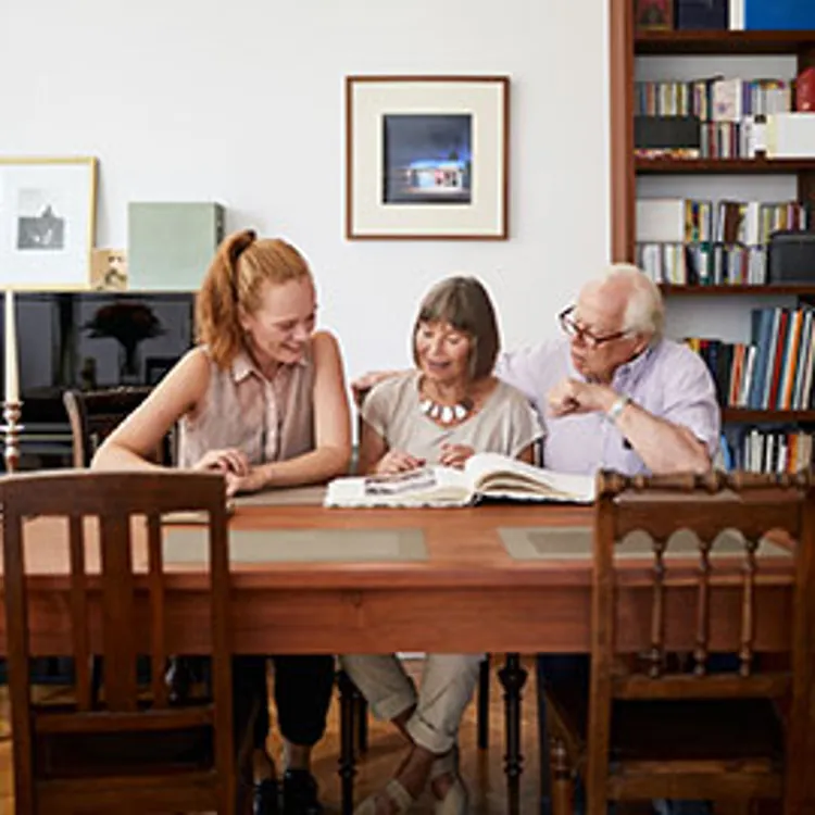 mature woman with her parents looking at a photo album at home