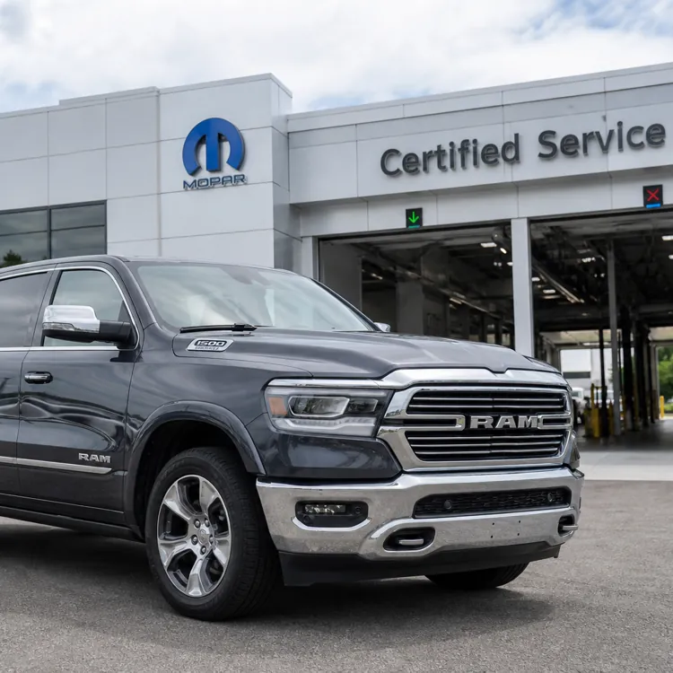 Gray Ram pickup truck parked in front of a Ram dealership and certified service center