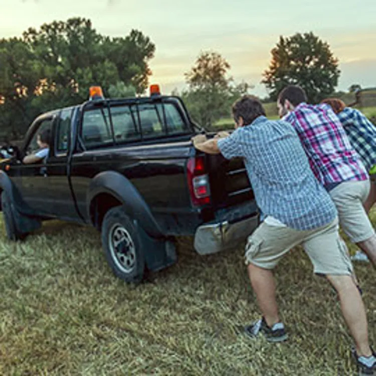 a group of guys helping to push-start a pickup truck