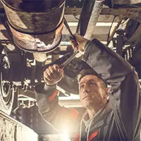 auto mechanic with socket wrench working on chassis