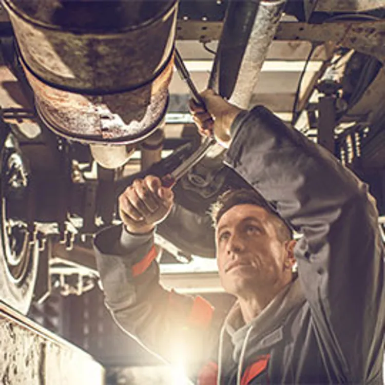 auto mechanic with socket wrench working on chassis
