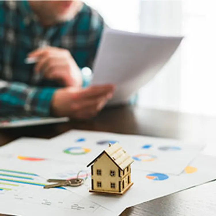 contract document with a house toy and key as paper weight