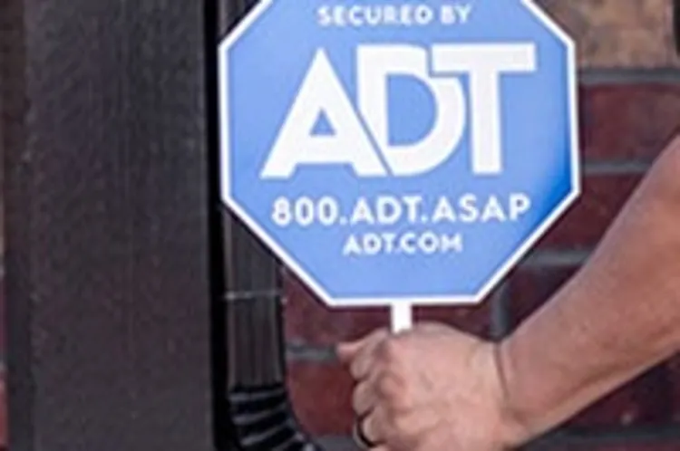 man inserting adt sign in front of home