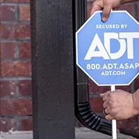 man inserting adt sign in front of home