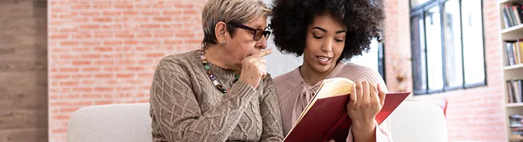 older adult woman reading with another woman
