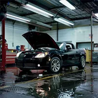 a saturn with the hood raised inside a repair shop