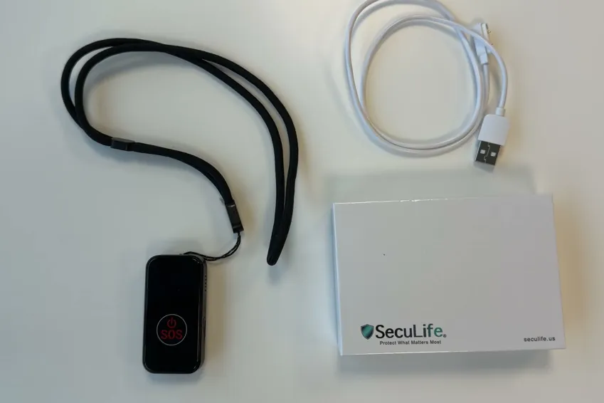 Overhead view of the SecuLife SOS pendant on its lanyard, the USB charging cable and the SecuLife box