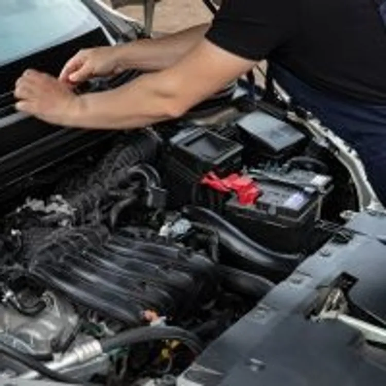 mechanic working under the hood of a car in a workshop