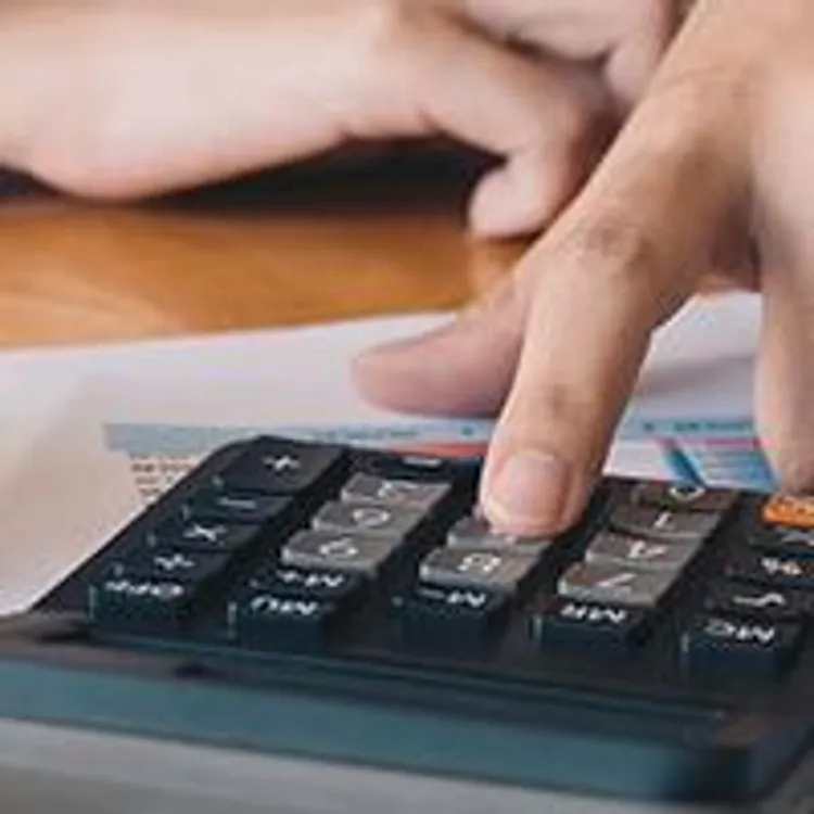 person computing with calculator and miniature house