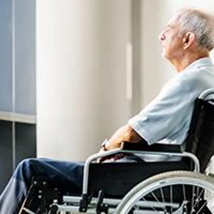 old man sitting in a wheelchair looking out a window