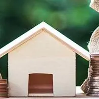stacks of coins around wooden model home