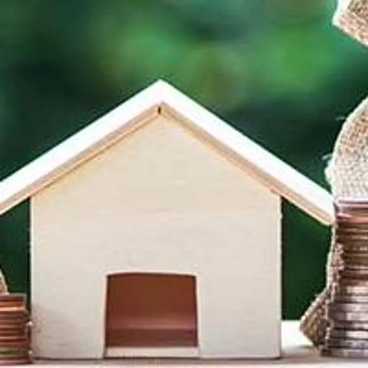 stacks of coins around wooden model home