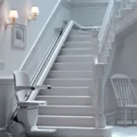a white stair lift installed at the bottom of some stairs
