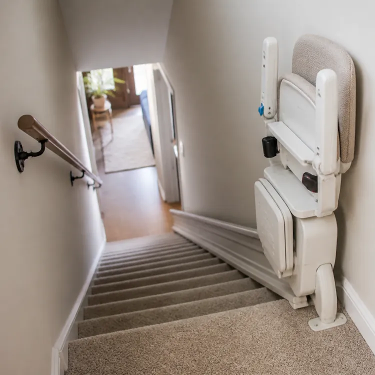Folded stair lift installed on a carpeted staircase in a residential home