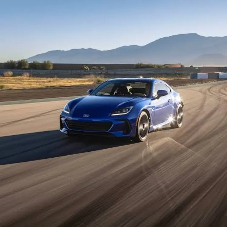 Blue sports car driving on a racetrack with mountains in the background