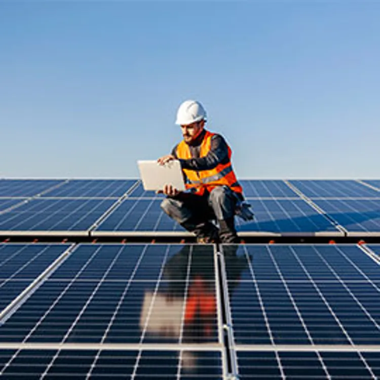 technician checking the data board while on top of a roof covered with solar panels