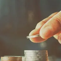 hand placing a coin on top of a stack
