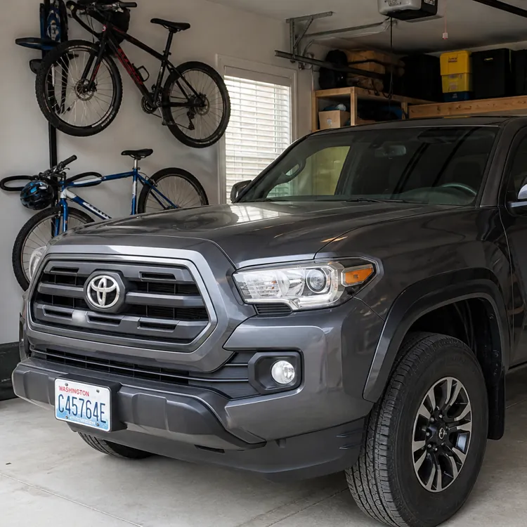Gray pickup truck parked in a clean garage with bicycles and storage shelves