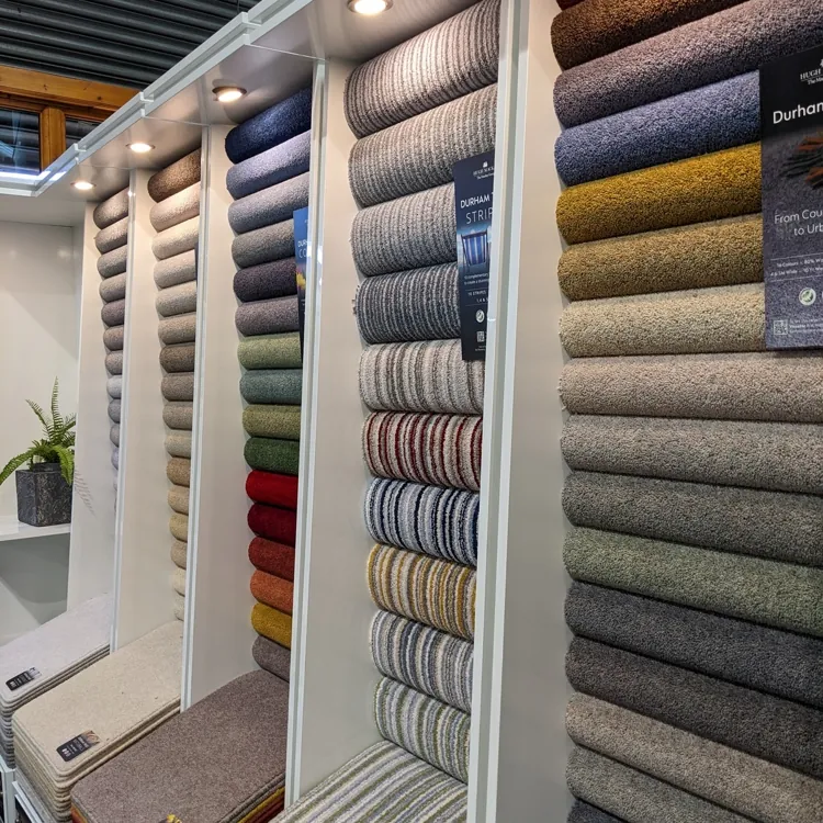 Multiple rolls of carpet in various colors and textures displayed vertically in a showroom