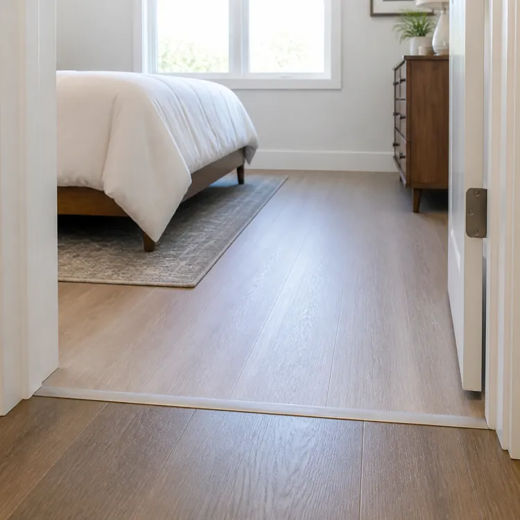 View through an open doorway showing a bedroom with wood flooring, bed, rug, and dresser