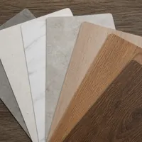 Six flooring samples with different colors and textures fanned out on a wooden surface