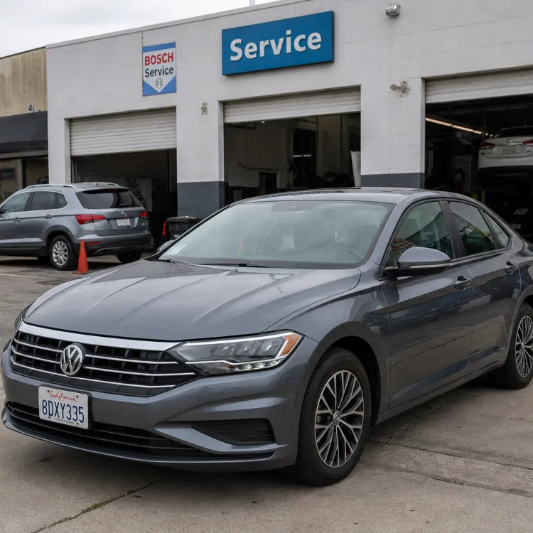 Gray sedan parked outside an auto repair shop with service bays open