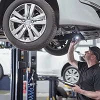 man inspecting the underside of a car in a service center
