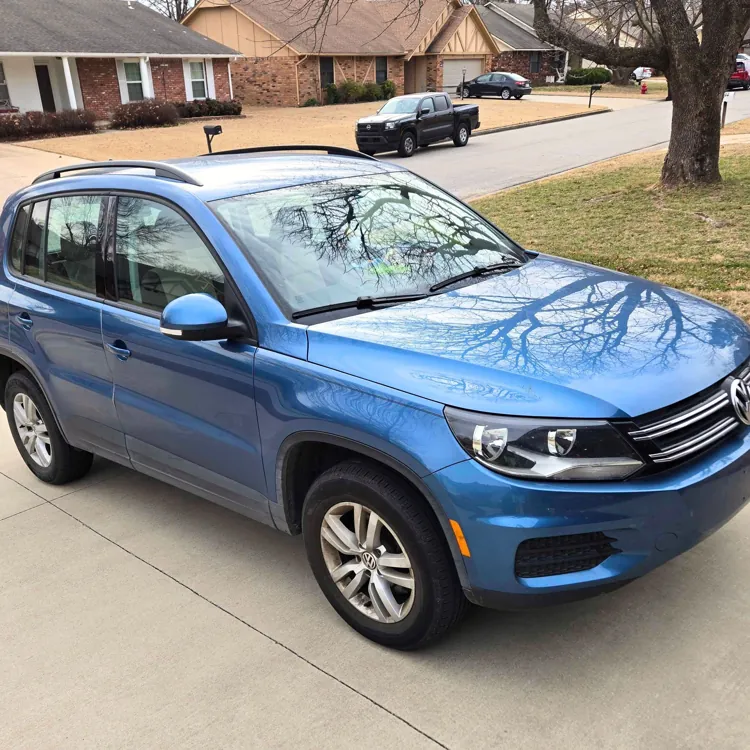 Blue SUV parked on a driveway in a suburban neighborhood with houses and bare trees visible.