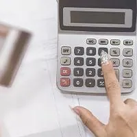 one hand holding credit cards with the other hand pressing calculator key
