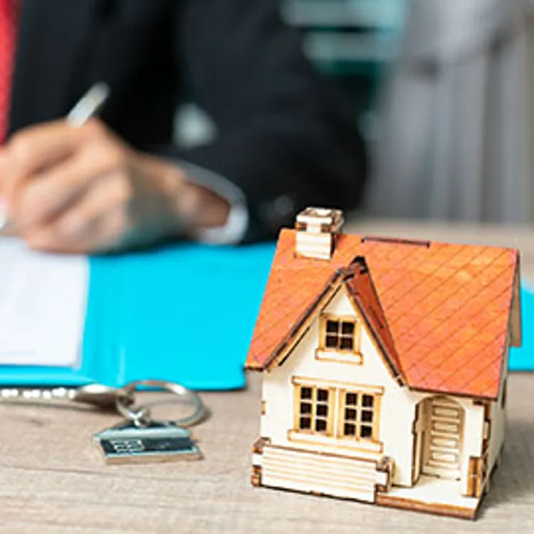 miniature house and keys with banker signing documents