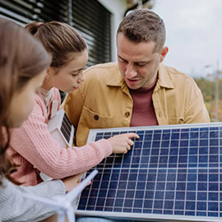 father and daughters holding a solar panel