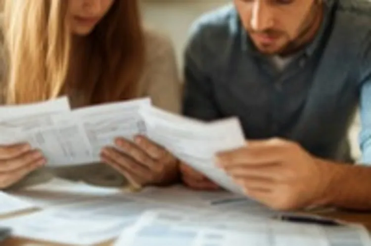 a couple looking at different bills on a kitchen table